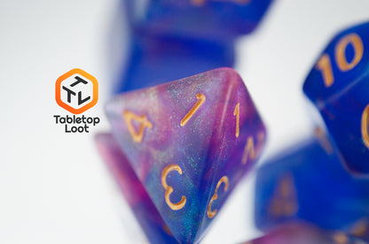 A close up of the D4 from the Blue Enchantress 7 piece dice set from Tabletop Loot with shimmering shades of pink, purple, and blue swirling resin and gold numbering.