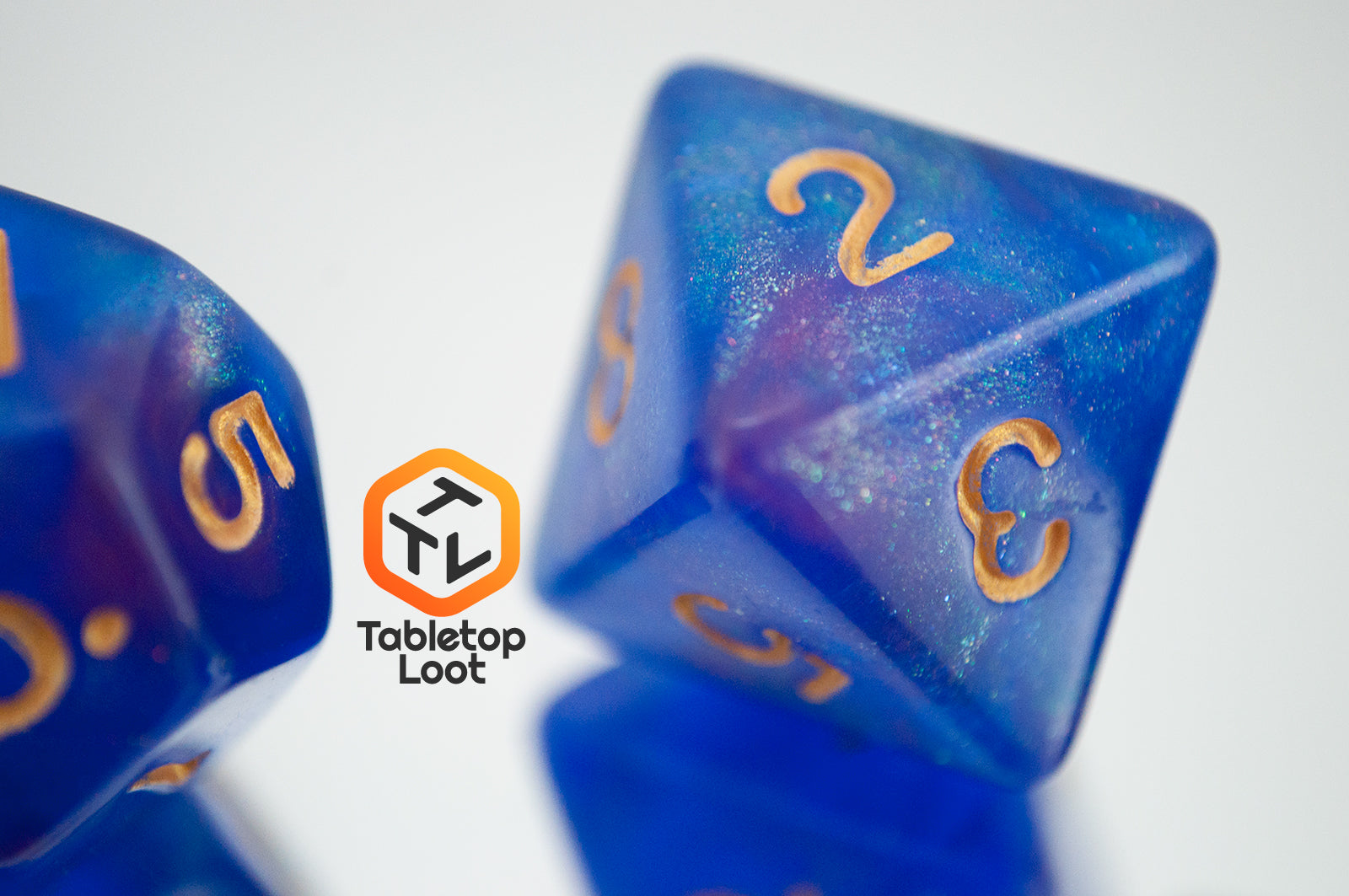 A close up of the D8 from the Blue Enchantress 7 piece dice set from Tabletop Loot with shimmering shades of pink, purple, and blue swirling resin and gold numbering.