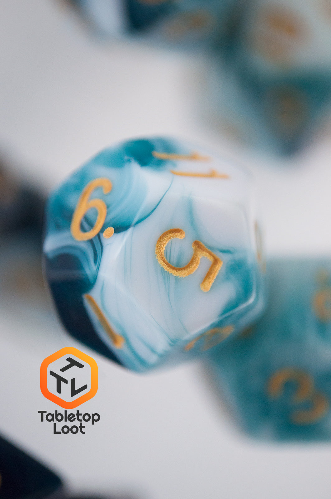 A close up of the D12 from the Blue Ink 7 piece dice set from Tabletop Loot with swirls of ocean blue and white resin and gold numbering.