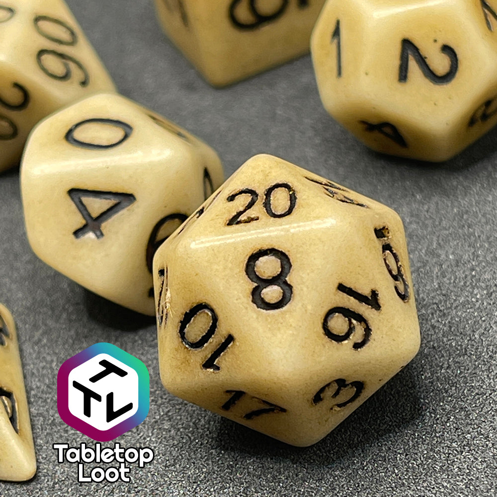 A close up of the D20 from the Bones of the Earth 7 piece dice set from Tabletop Loot with a bone colored and textured appearance and black numbering.