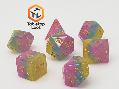 The Candyland 7 piece dice set from Tabletop Loot with layers of yellow, blue, and pink glittery resin and gold numbering.