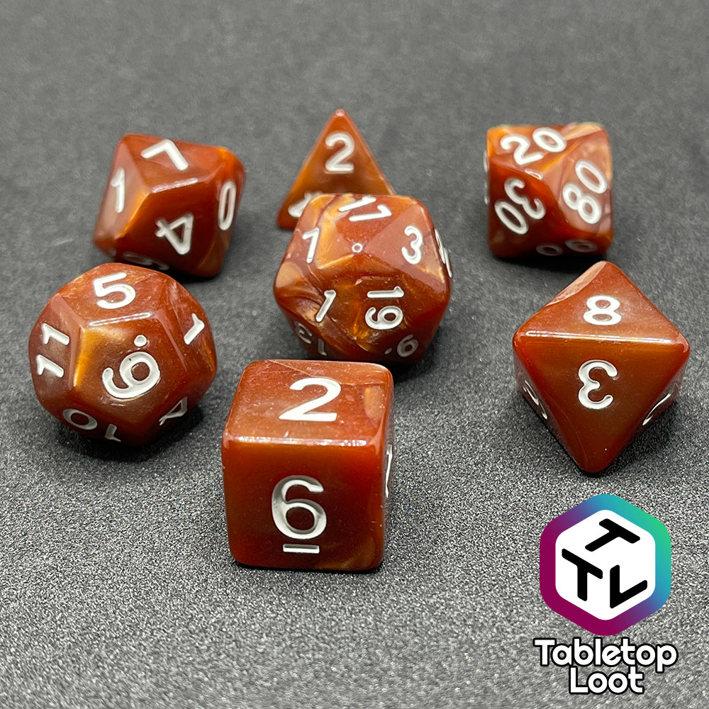The Caramels 7 piece dice set from Tabletop Loot with pearlescent swirls of caramel brown color and white numbering.
