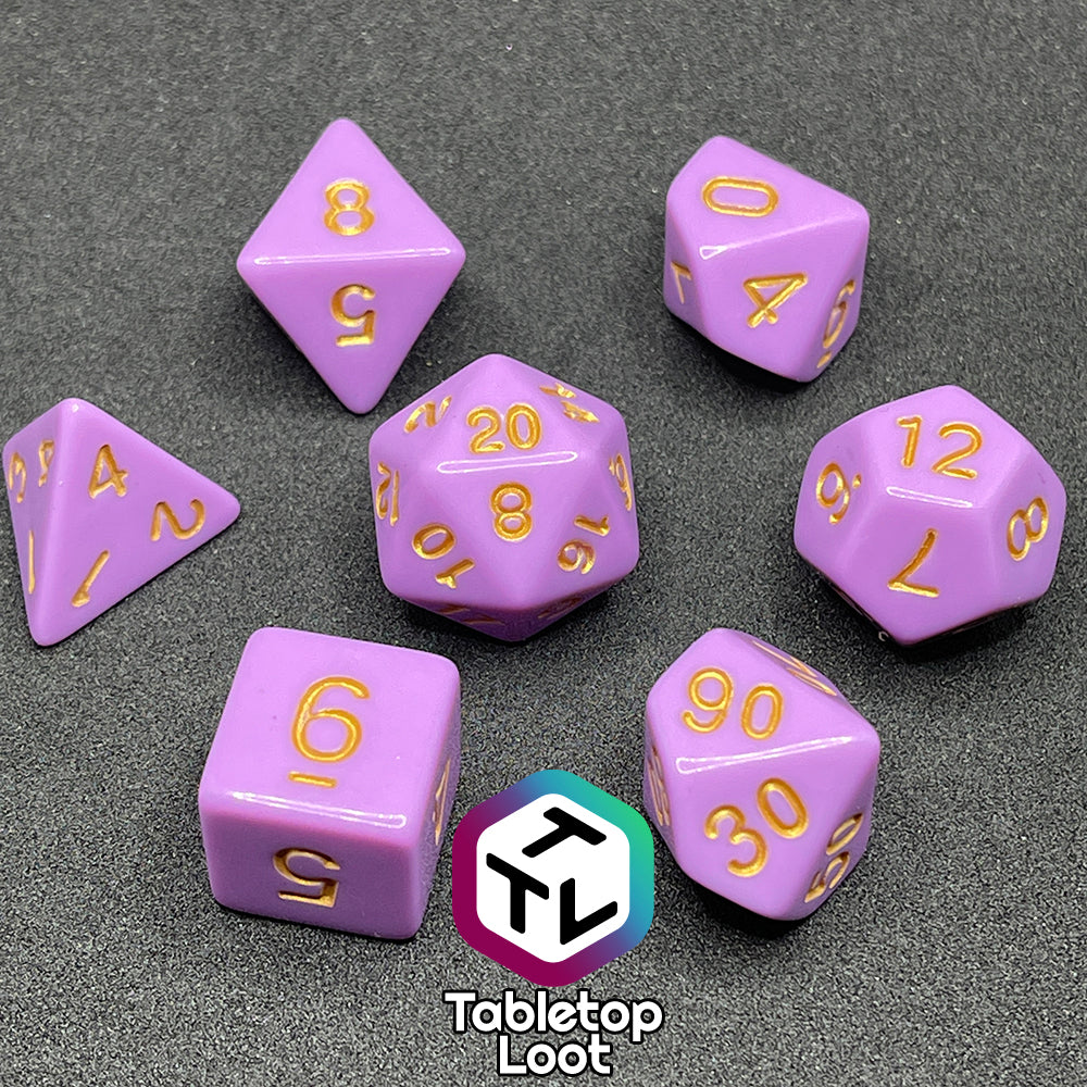 The Carnations 7 piece dice set from Tabletop Loot with gold numbering on solid pink faces.