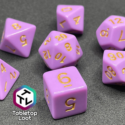 A close up of the Carnations 7 piece dice set from Tabletop Loot with gold numbering on solid pink faces.
