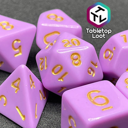 A close up of the Carnations 7 piece dice set from Tabletop Loot with gold numbering on solid pink faces.