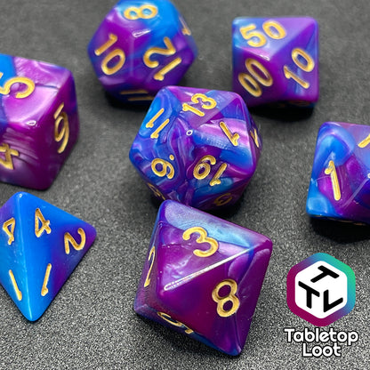 A close up of the Carnival 7 piece dice set from Tabletop Loot with swirls of blue and purple and gold numbering.