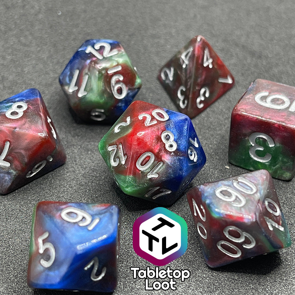 A close up of the Changeling 7 piece dice set from Tabletop Loot with swirls of pearlescent red, green, and blue and silver numbering.