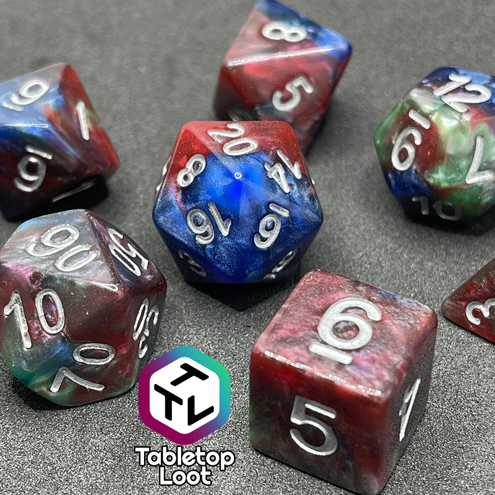 A close up of the Changeling 7 piece dice set from Tabletop Loot with swirls of pearlescent red, green, and blue and silver numbering.