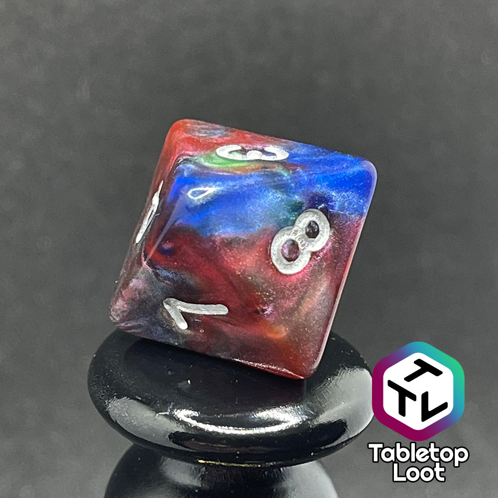 A close up of the D8 from the Changeling 7 piece dice set from Tabletop Loot with swirls of pearlescent red, green, and blue and silver numbering.