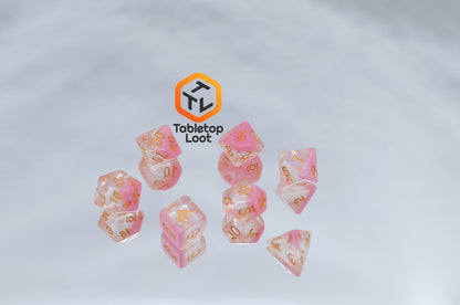 The Cherry Blossom 7 piece dice set from Tabletop Loot with a layer of glittery pink resin in clear glittery resin and gold numbers.