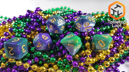 The Commune with Nature 7 piece dice set from Tabletop Loot with swirls of green and purple and gold numbering.