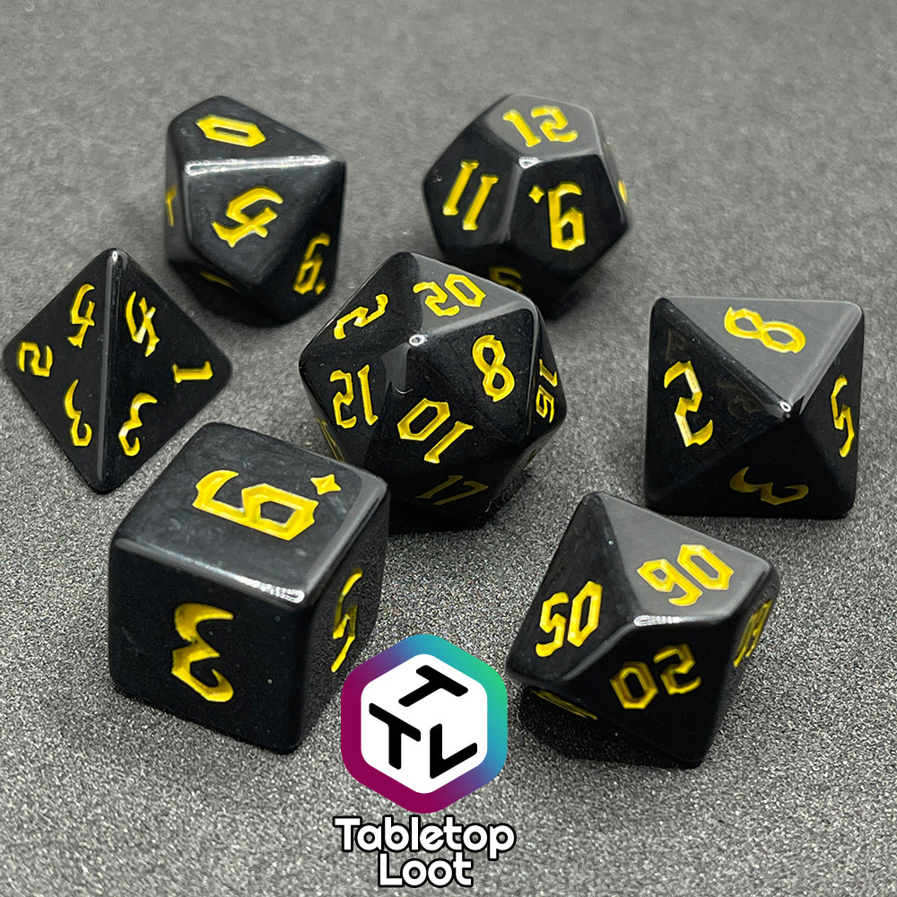 The Construct 7 piece dice set from Tabletop Loot with bright yellow bold gothic numbers on a highly reflective solid black surface.