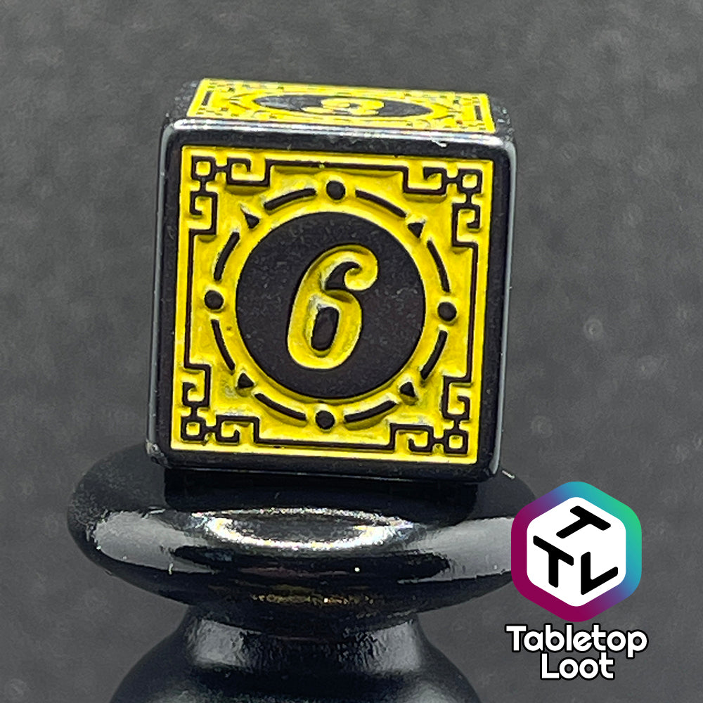 A close up of the D6 from the Lament Configuration 7 piece dice set from Tabletop Loot with black borders, swirls, and stars and a bright yellow relief and numbering.