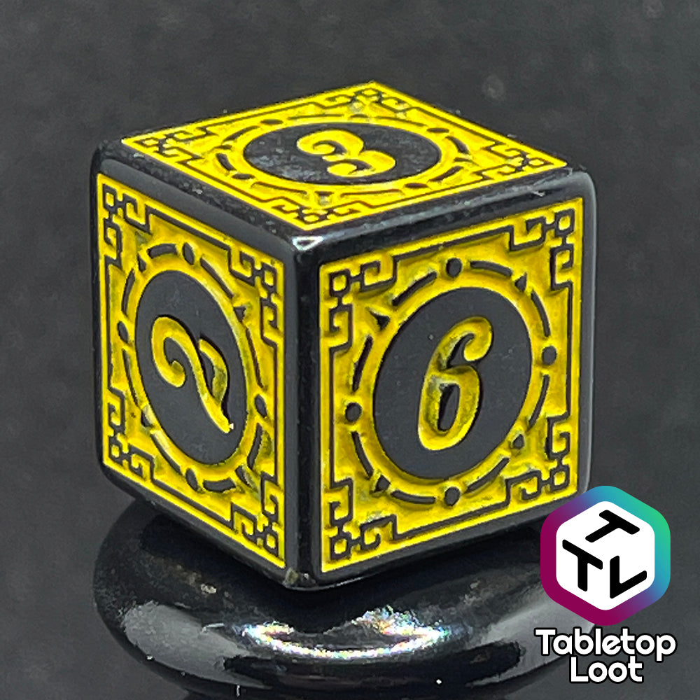 A close up of the D6 from the Lament Configuration 7 piece dice set from Tabletop Loot with black borders, swirls, and stars and a bright yellow relief and numbering.