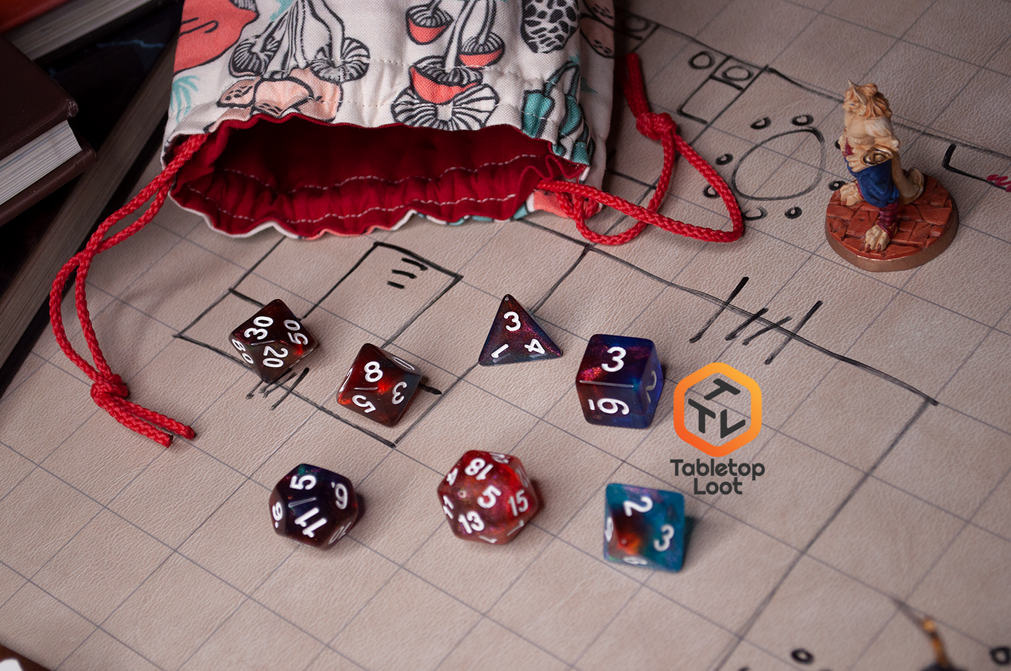 The Interstellar 7 piece dice set from Tabletop Loot with swirling shades of shimmery red and blue resin and white numbering.