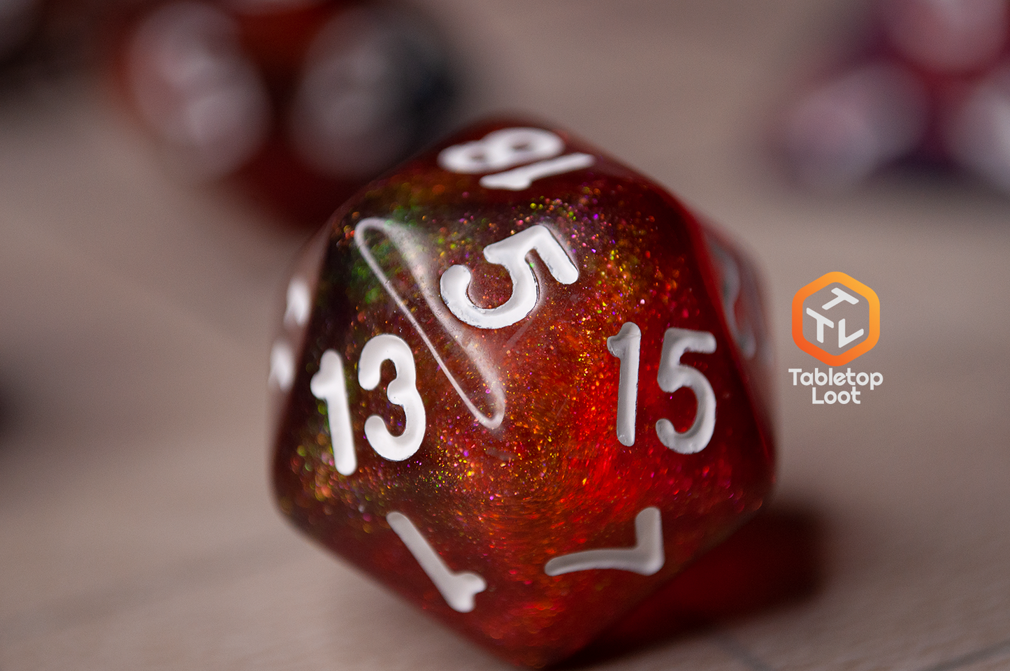 A close up of the D20 from the Interstellar 7 piece dice set from Tabletop Loot with swirling shades of shimmery red and blue resin and white numbering.