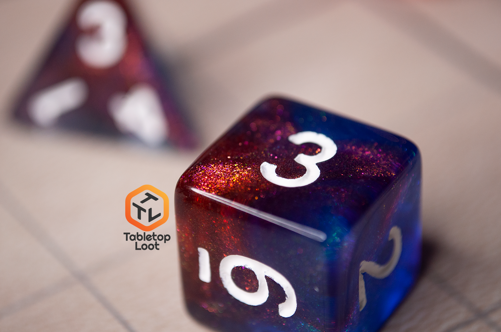 A close up of the D6 from the Interstellar 7 piece dice set from Tabletop Loot with swirling shades of shimmery red and blue resin and white numbering.