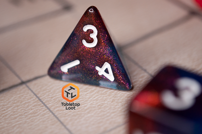 A close up of the D4 from the Interstellar 7 piece dice set from Tabletop Loot with swirling shades of shimmery red and blue resin and white numbering.