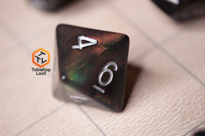 A close up of the D8 from the Dark Star 7 piece dice set from Tabletop Loot with glittering swirls of pink, green, gold, and blue, inked in silver.