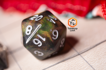 A close up of the D20 from the Dark Star 7 piece dice set from Tabletop Loot with glittering swirls of pink, green, gold, and blue, inked in silver.