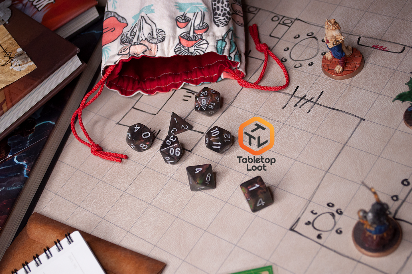 The Dark Star 7 piece dice set from Tabletop Loot with glittering swirls of pink, green, gold, and blue, inked in silver, spills across a gaming table.