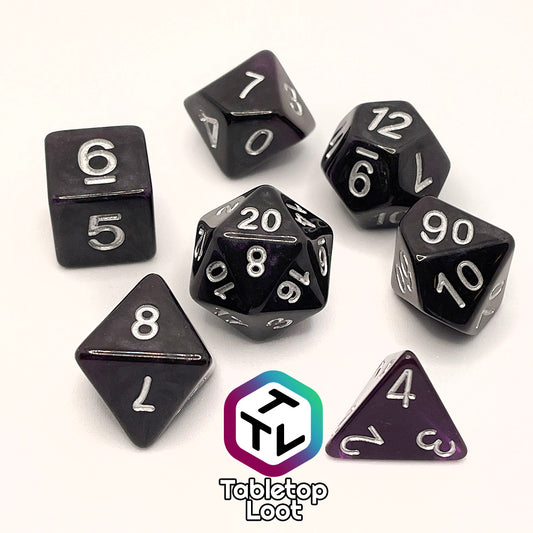 The Darkness 7 piece dice set from Tabletop Loot; translucent purple so dark it looks black except where the light peeks through in corners, inked in silver.