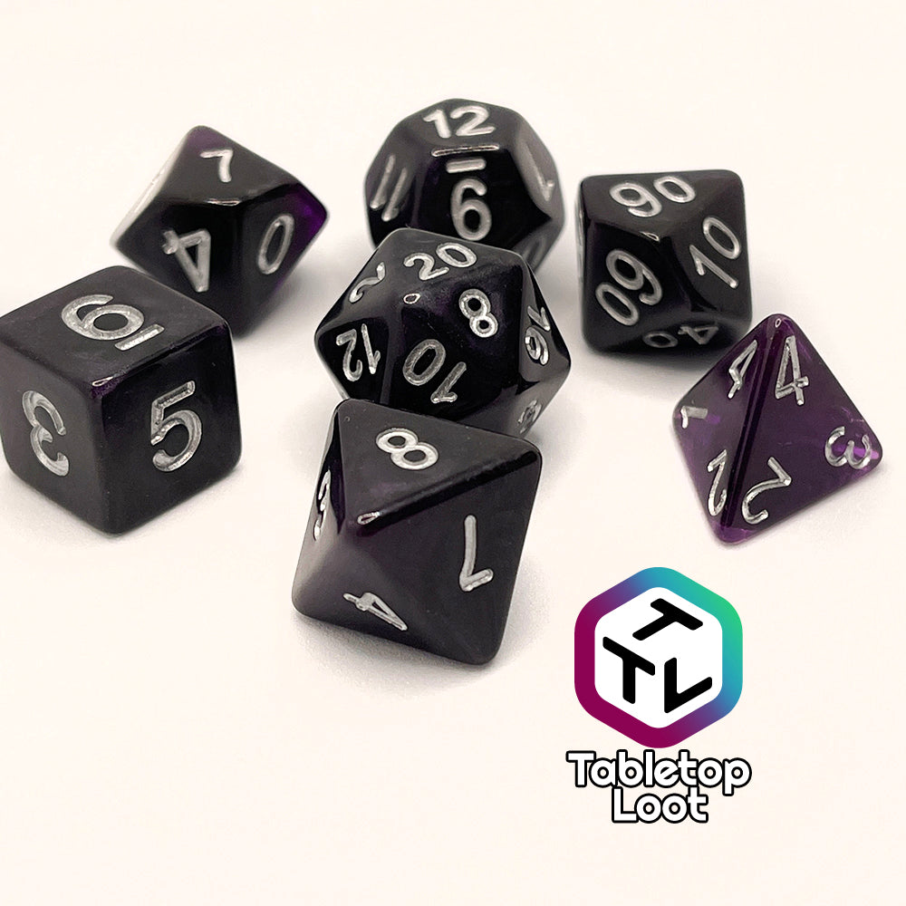 The Darkness 7 piece dice set from Tabletop Loot; translucent purple so dark it looks black except where the light peeks through in corners, inked in silver.