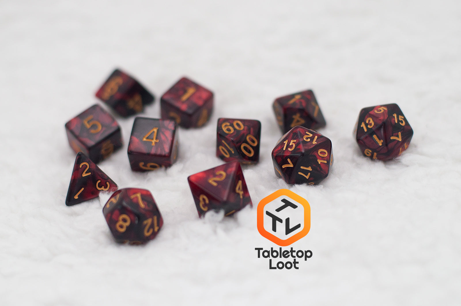 The Demon Stones 11 piece dice set from Tabletop Loot with deep red swirled with black resin and gold numbering.