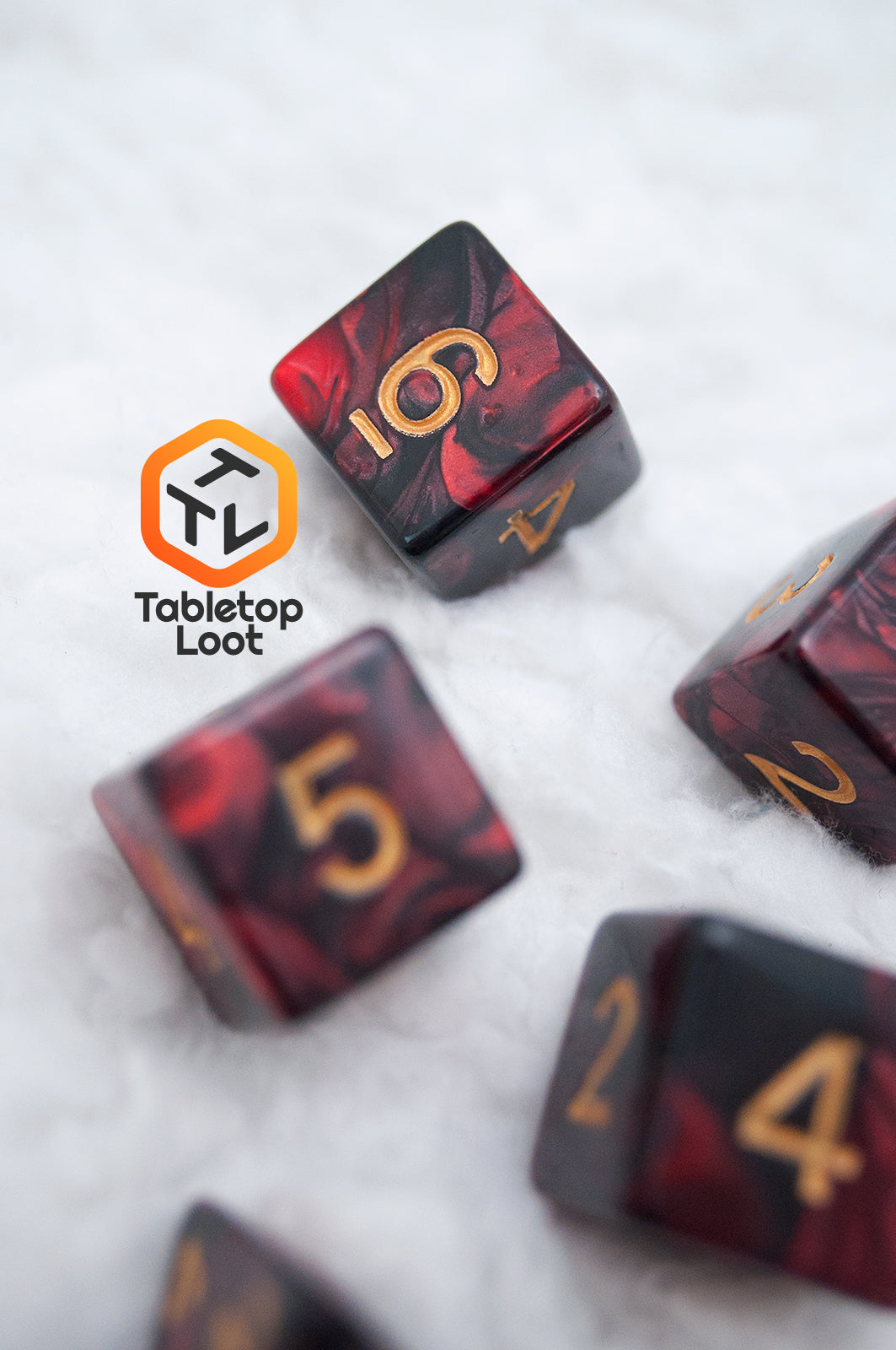 A close up of the Demon Stones 11 piece dice set from Tabletop Loot with deep red swirled with black resin and gold numbering.