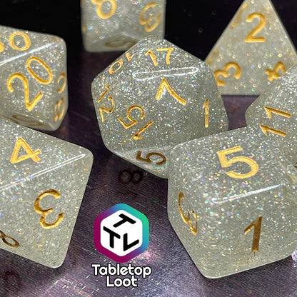 A close up of the Diamond Dust 7 piece dice set from Tabletop Loot packed with silver glitter and gold numbering.