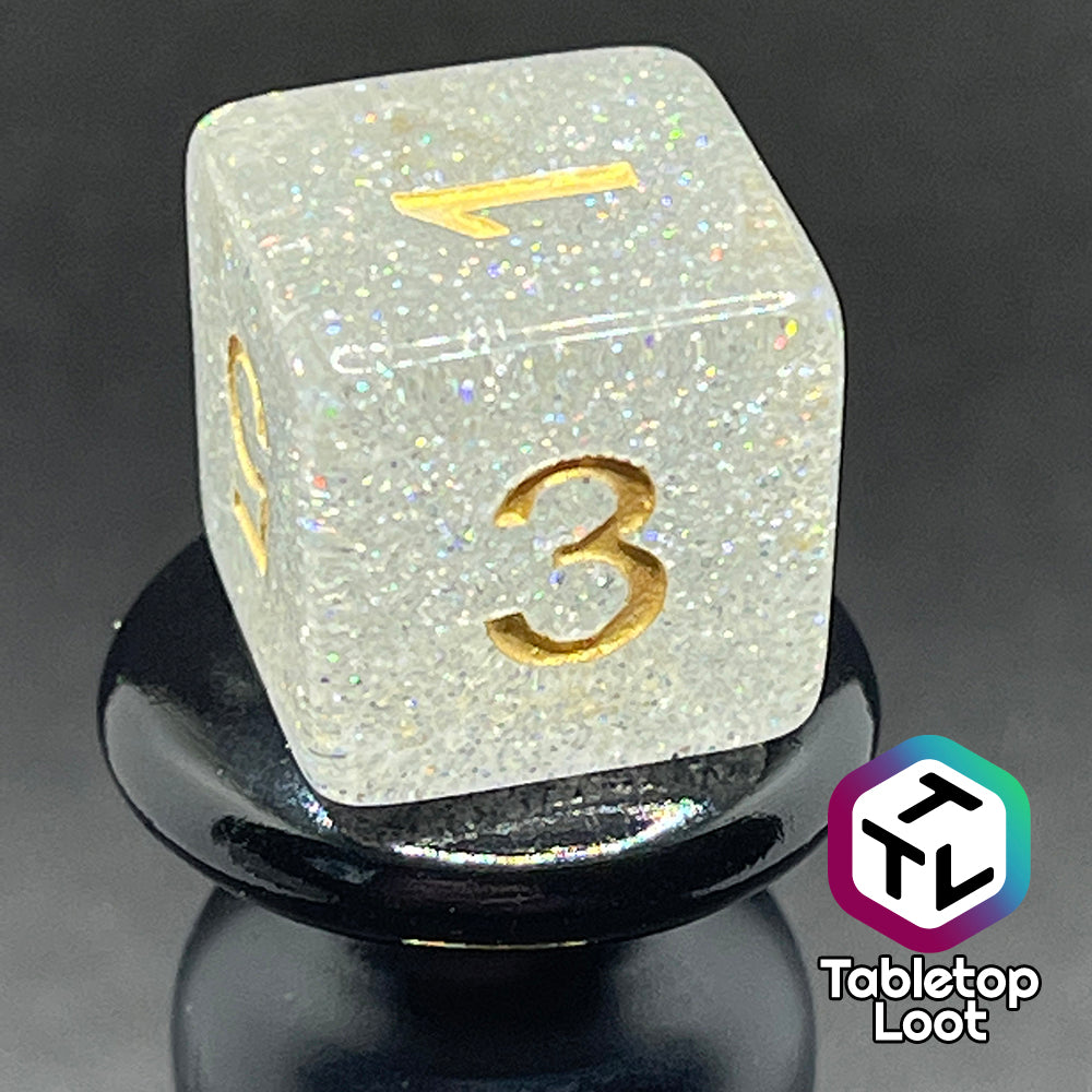 A close up of the D6 from the Diamond Dust 7 piece dice set from Tabletop Loot packed with silver glitter and gold numbering.