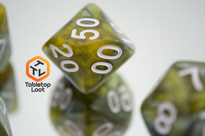 A close up of the percentile die from the Disintegrate 7 piece dice set from Tabletop Loot with swirls of silver and gold and white numbering.