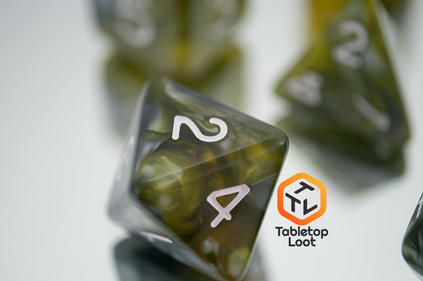 A close up of the D8 from the Disintegrate 7 piece dice set from Tabletop Loot with swirls of silver and gold and white numbering.