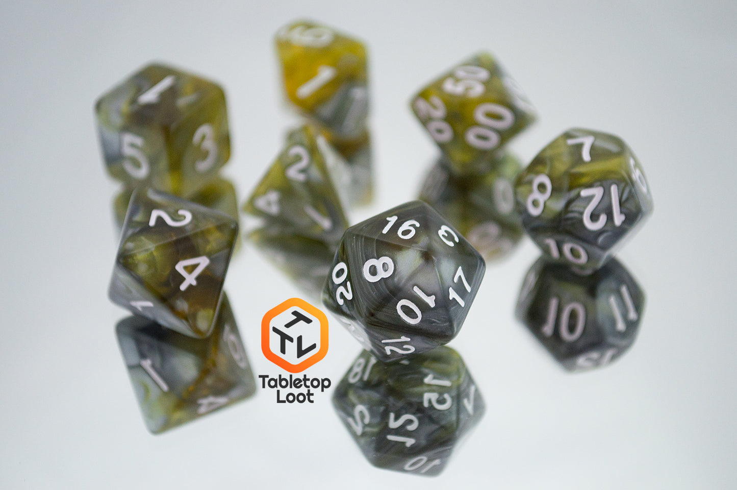 The Disintegrate 7 piece dice set from Tabletop Loot with swirls of silver and gold and white numbering.