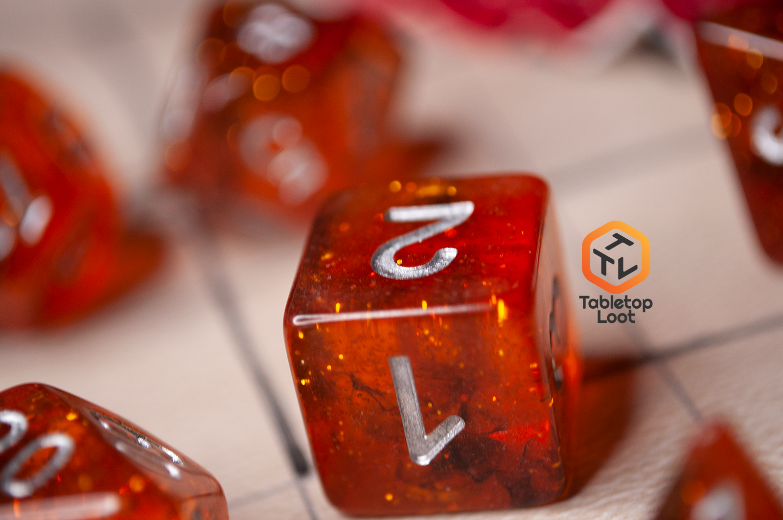 A close up of the Dissonant Whispers 7 piece dice set from Tabletop Loot with swirls of black in sparkling amber color, inked in silver.