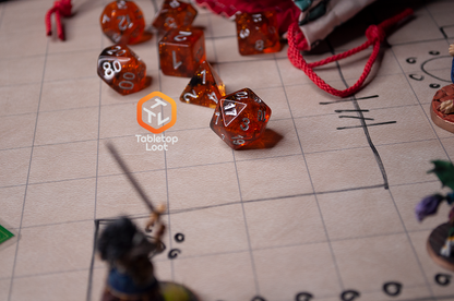 The Dissonant Whispers 7 piece dice set from Tabletop Loot with swirls of black in sparkling amber color, inked in silver, rolls across a game surface.