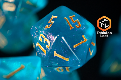 A close up of the D20 from the Draconic Seas 7 piece dice set from Tabletop Loot with shimmering translucent blue resin and gold numbering.