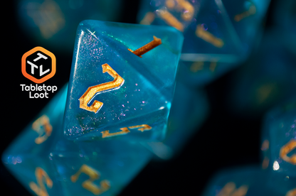 A close up of the D8 from the Draconic Seas 7 piece dice set from Tabletop Loot with shimmering translucent blue resin and gold numbering.