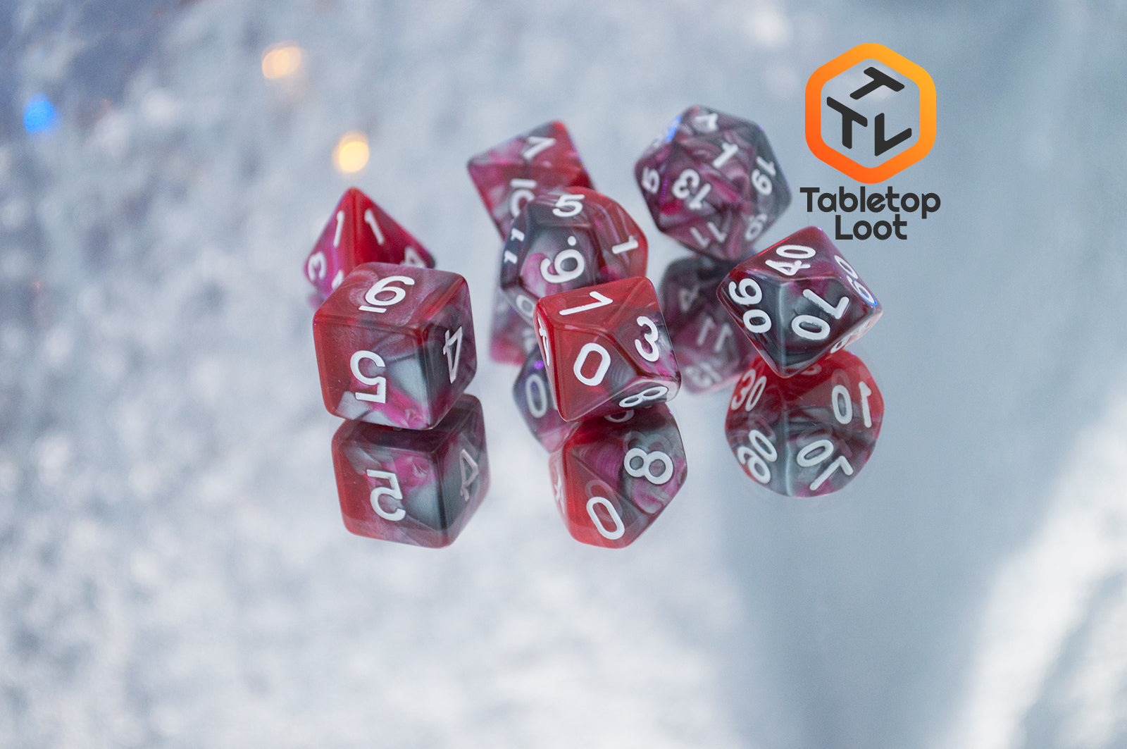 The Dragon's Blood 7 piece dice set from Tabletop Loot with swirled red and grey resin and white numbering.