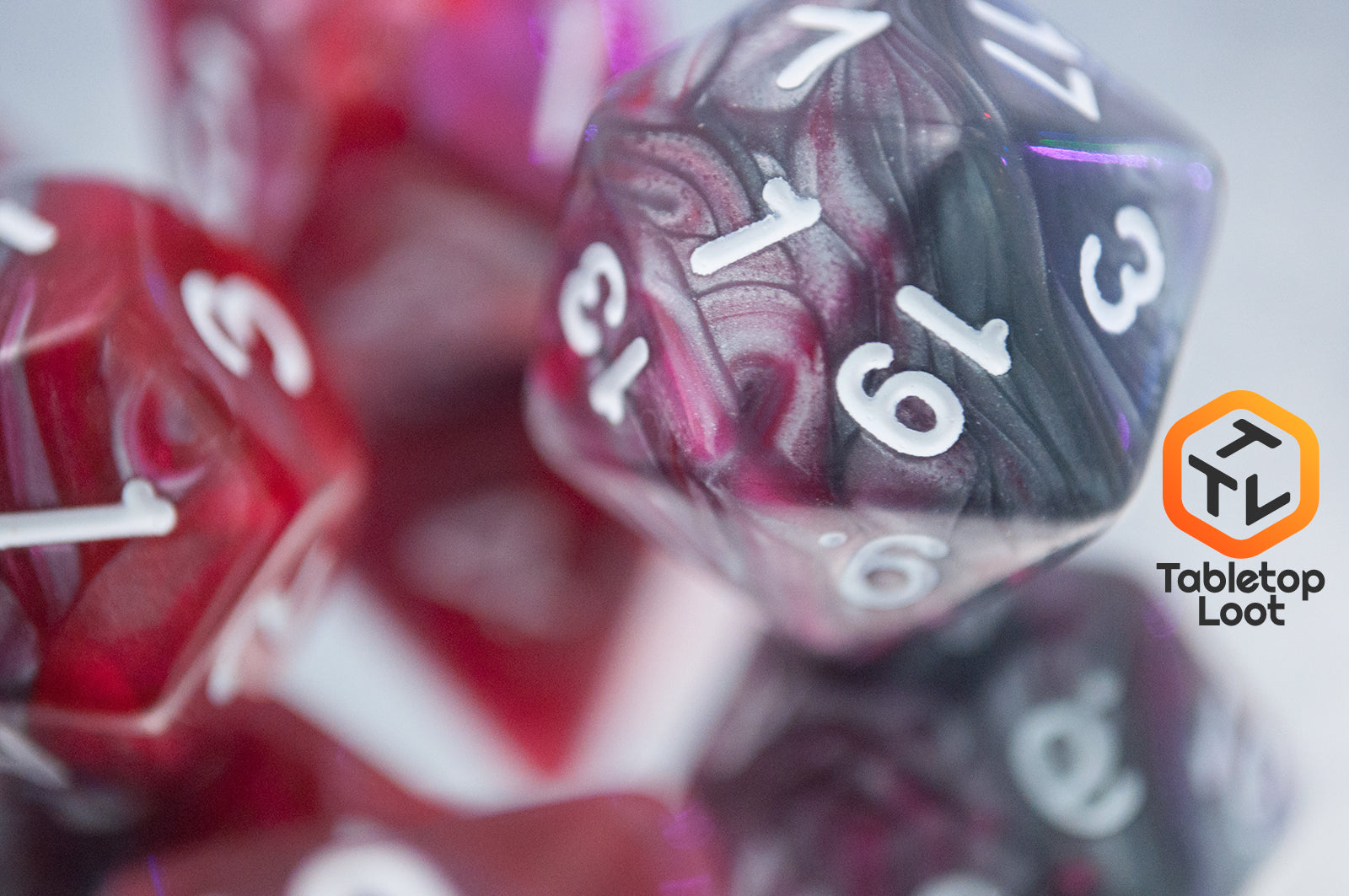 A close up of the D20 from the Dragon's Blood 7 piece dice set from Tabletop Loot with swirled red and grey resin and white numbering.