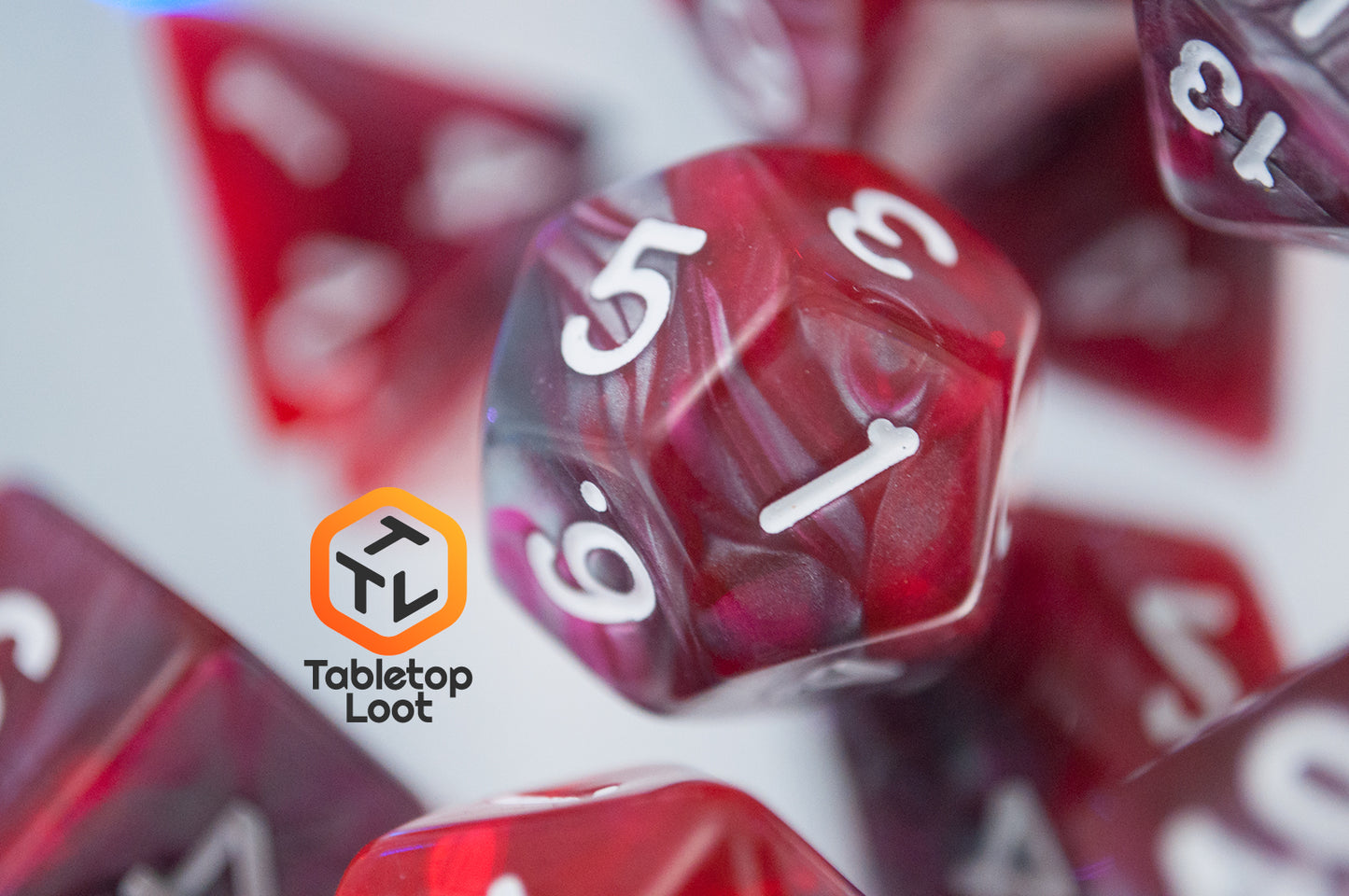 A close up of the D12 from the Dragon's Blood 7 piece dice set from Tabletop Loot with swirled red and grey resin and white numbering.
