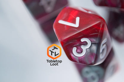 A close up of the D10 from the Dragon's Blood 7 piece dice set from Tabletop Loot with swirled red and grey resin and white numbering.