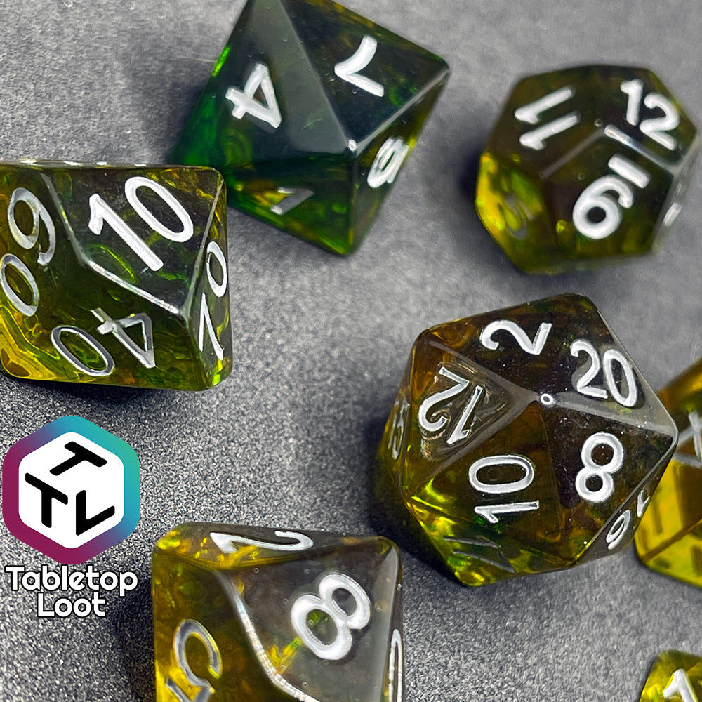 7 piece translucent yellow polyhedral dice set with green ink swirls and white numbers.