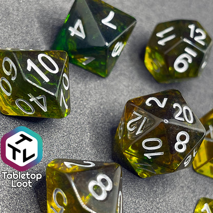 7 piece translucent yellow polyhedral dice set with green ink swirls and white numbers.