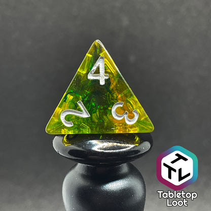 Translucent yellow d4 with green ink swirls and white numbers.