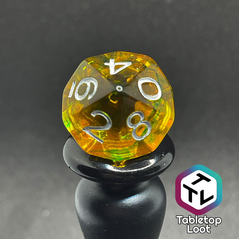 Translucent yellow d10 with green ink swirls and white numbers.