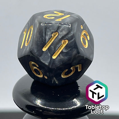 A close up of the D12 from the Dreadnaught 7 piece dice set from Tabletop Loot with swirls of pearlescent black and gold numbering.