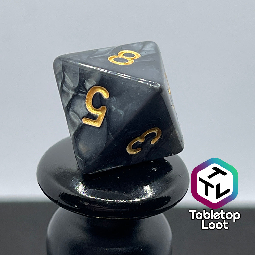 A close up of the D8 from the Dreadnaught 7 piece dice set from Tabletop Loot with swirls of pearlescent black and gold numbering.