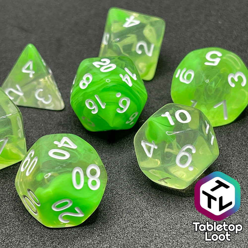 A close up of the Ectoplasm 7 piece dice set from Tabletop Loot with swirls of lime green in clear resin and white numbering.