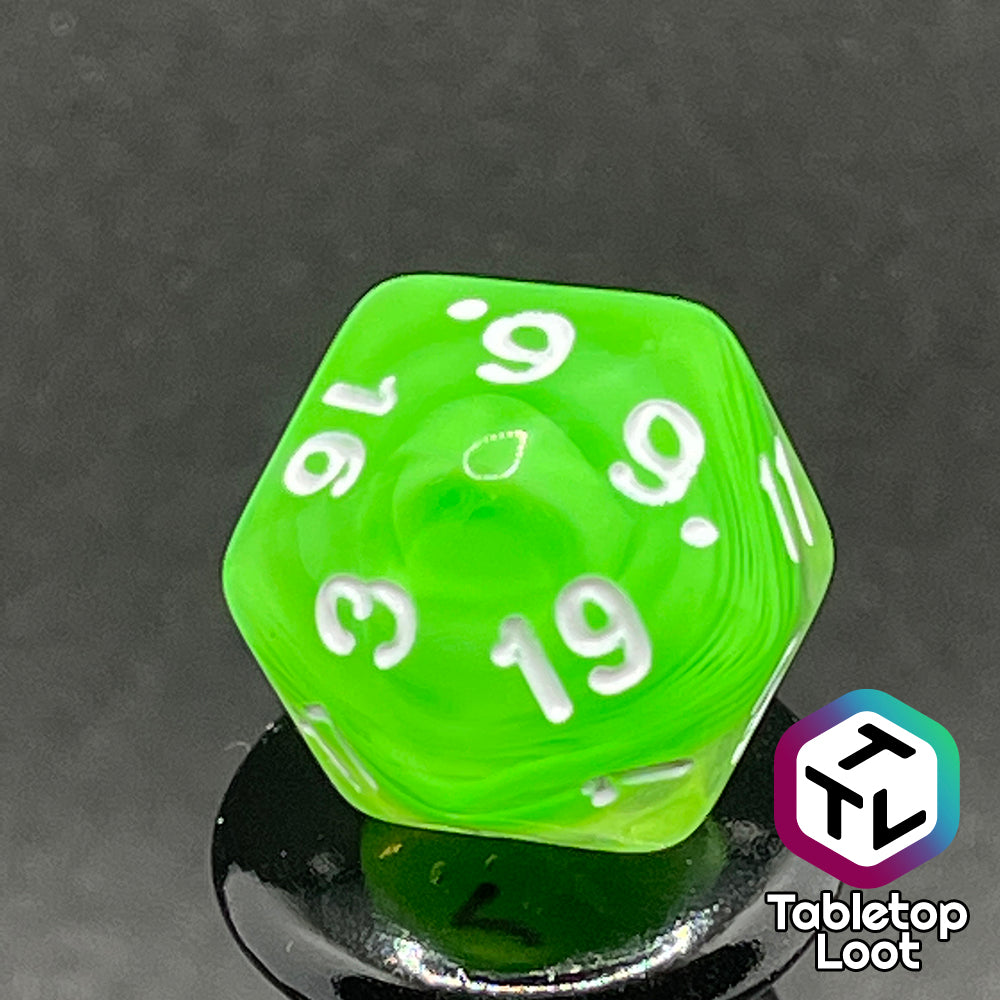 A close up of the D20 from the Ectoplasm 7 piece dice set from Tabletop Loot with swirls of lime green in clear resin and white numbering.